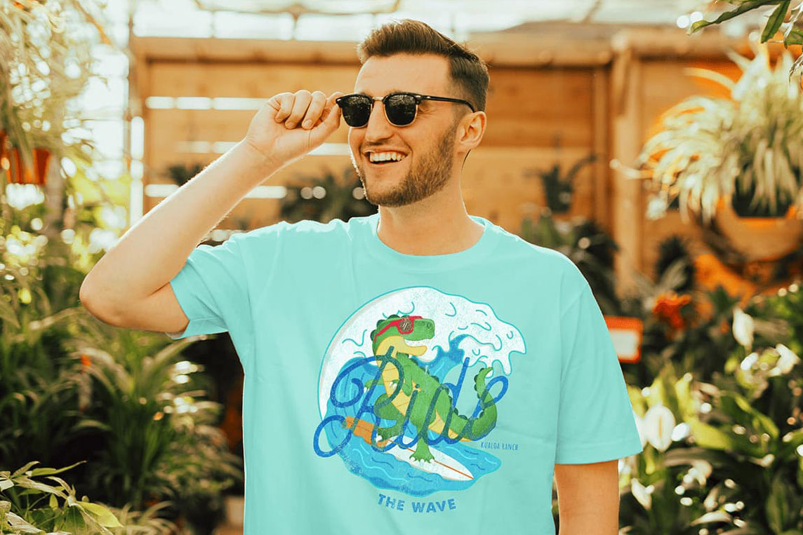 Male with sunglasses wearing a t-rex surfing shirt